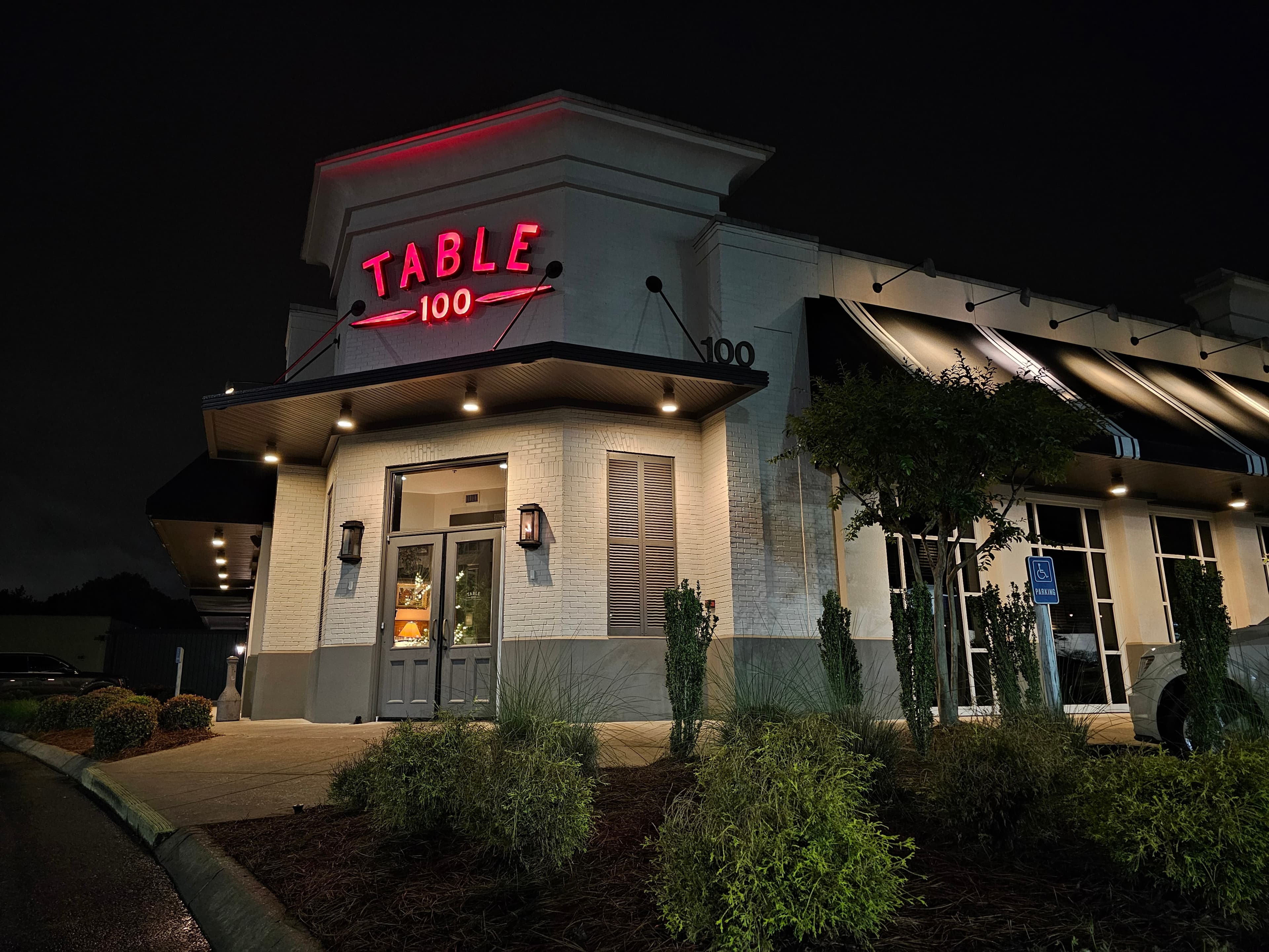 Table 100 illuminated neon storefront at night